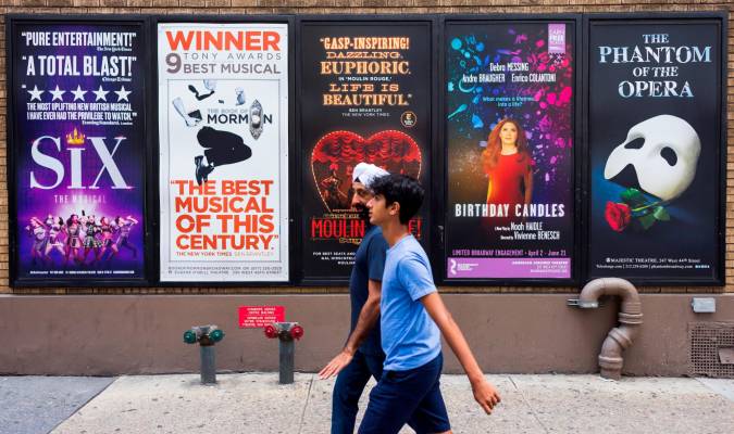 Personas paseando en Nueva York delante de carteles de musicales. / EFE
