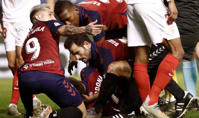 Los jugadores de Osasuna Rubén García (d) y Chimy Ávila (i) acuden en ayuda de su compañero Marc Cardona (c) que cayó al suelo tras un encontronazo con un jugador del Sevilla. EFE/Jesús Diges