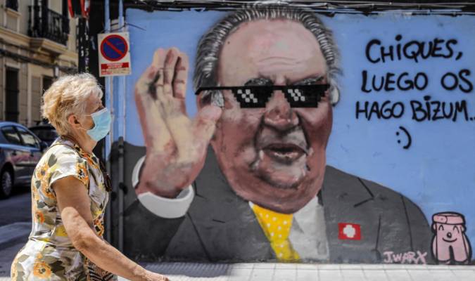 Una mujer pasa junto al graffiti del rey emérito Juan Carlos I pintado en una céntrica calle de Valencia por el artista J. Warx. / Rober Solsona - E.P.