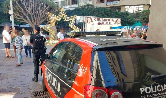 Agente de la Policía Canaria junto a un coche patrulla.