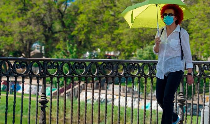 Mujer pasea con un paraguas amarillo por el puente de Triana. / Eduardo Briones EP