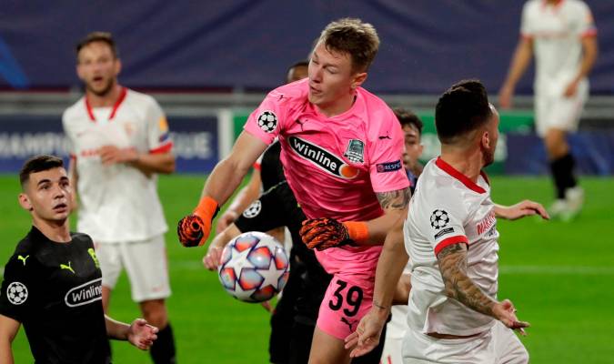 El portero del Krasnodar Ayvey Safonov (c), intenta despejar ante el centrocampista argentino del Sevilla Lucas Ocampos (d). EFE/Julio Muñoz