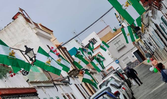 Vista de una calle de Guillena con los balcones y ventanas luciendo las banderas de Andalucía repartidas por el Ayuntamiento (Foto: Ayuntamiento de Guillena).