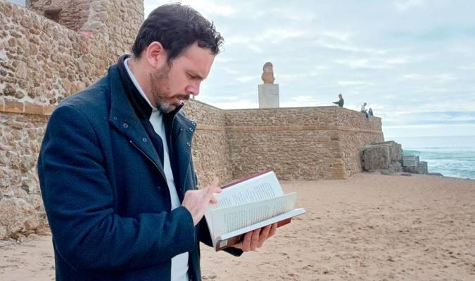 Luis Rossi posa con su novela en la playa de La Caleta en Cádiz junto al busto de Paco Alba.
