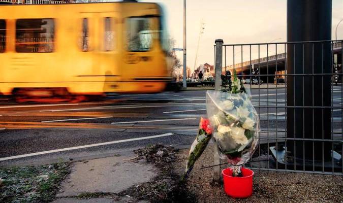 Un tranvía pasa junto a los ramos de flores depositados en el lugar del tiroteo de Utrecht. / EFE