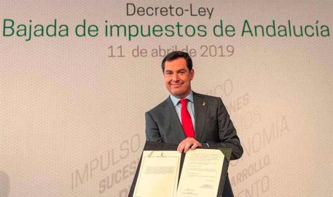 El presidente andaluz, Juanma Moreno, tras firmar el decreto que rebaja varios de los impuestos de titularidad autonómica y el tramo autonómico el IRPF. / EFE