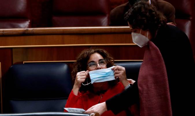 La ministra de Hacienda, María Jesús Montero, se coloca la mascarilla durante el pleno del Congreso de los Diputados, este miércoles. / BALLESTEROS-EFE