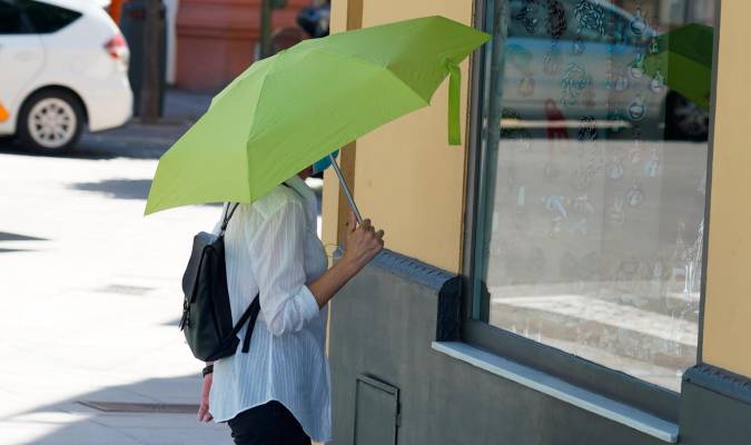 Mujer pasea con un paraguas amarillo por el puente de triana, / Eduardo Briones. EP