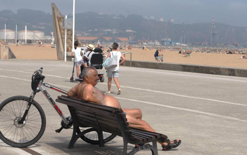 Un hombre descansa frente a la playa de Poniente, en Gijón, este viernes en una jornada de intenso calor. EFE/ Juan González