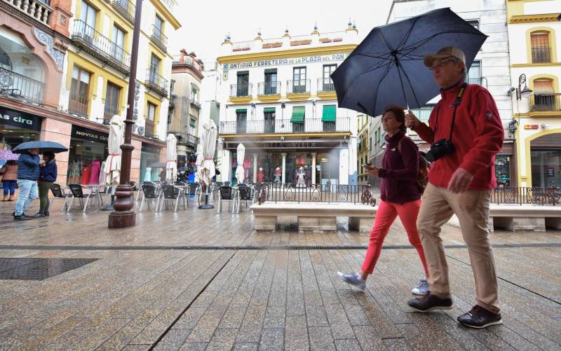 Dos turistas con paraguas pasean por el centro de Sevilla. Foto: Jesús Barrera.