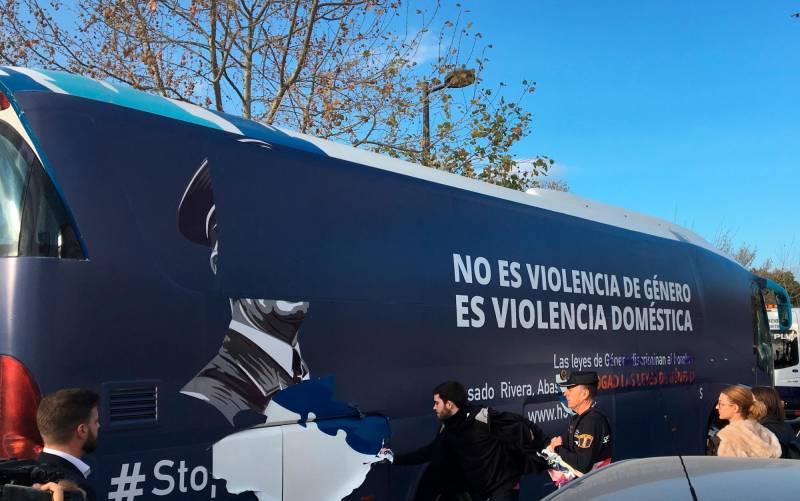 Un grupo de personas arranca los vinilos del autobús de HazteOír en Valencia. / EFE