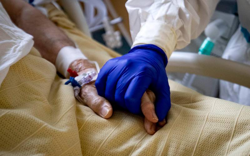 Un sanitario coge la mano de un enfermo de coronavirus. / Massimo Percossi - EFE