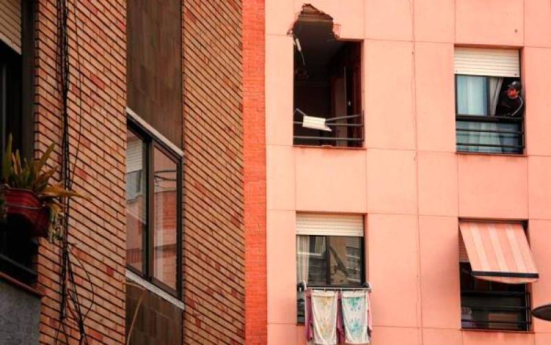 Un joven observa la ventana por dónde entró el trozo de metal procedente de la explosión en la Petroquímica, causando la muerte de un vecino de este edificio. / EFE