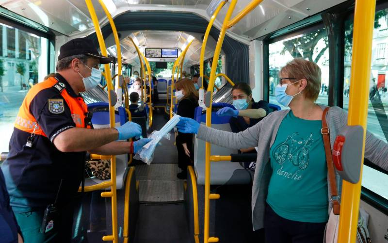 Miembros de protección civil de Málaga entregan mascarillas a los pasajeros de autobuses. / Álex Zea - E.P.