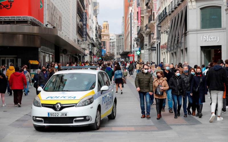Un coche de la policía local circula entre los transeúntes que pasean por una de las calles comerciales anexas a la Puerta del Sol. EFE/Emilio Naranjo