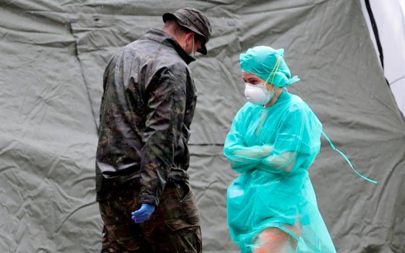Una sanitaria pasa junto a un militar ante un hospital de campaña montado cerca del acceso de Urgencias del Hospital Gregorio Marañón, este martes, en Madrid. EFE/JuanJo Martín