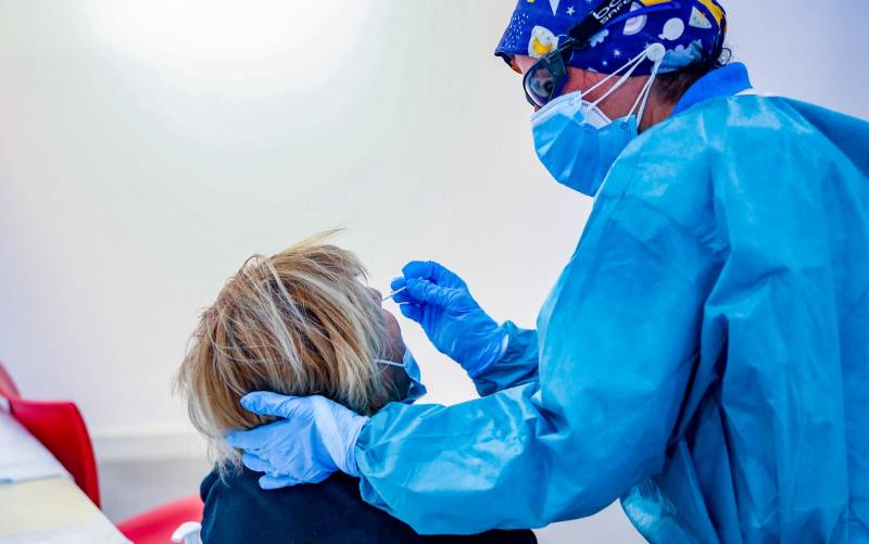 Un sanitario toma muestras a una mujer a través de un frotis de nariz para realizar un test de antígenos. / E.P.