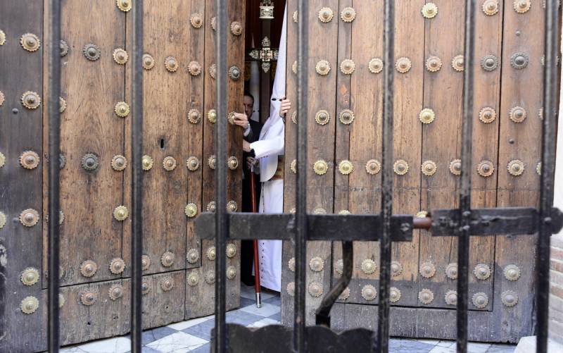Un nazareno de la Sagrada Cena abre el portón de la iglesia para comenzar la estación de penitencia. Foto: Manuel Gómez. 