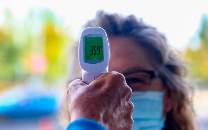 Un sanitario le toma la temperatura a una mujer. / Ricardo Rubio - E.P.
