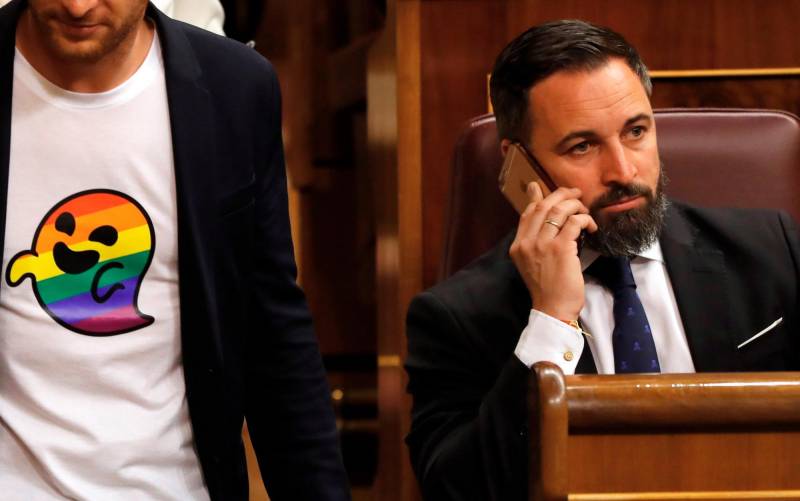 El diputado del PSC Arnau Ramirez (i) con una camiseta con el icono ‘gaysper’, pasa ante el presidente de VOX, Santiago Abascal (d), en uno de los escaños del Congreso de los Diputados. EFE/Ballestros