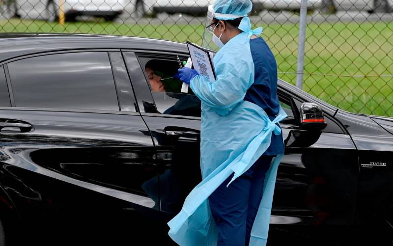 Un sanitario hace un test de antígenos en un coche.