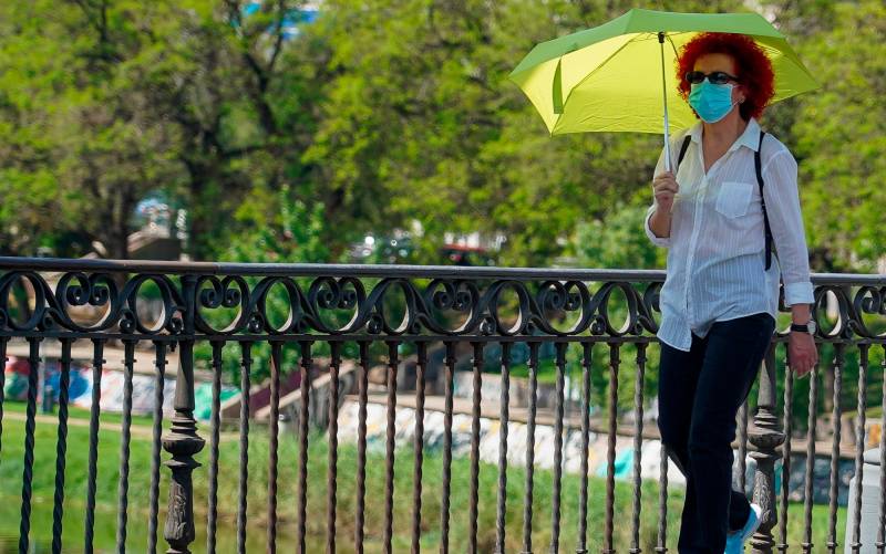 Mujer pasea con un paraguas amarillo por el puente de Triana. / Eduardo Briones EP