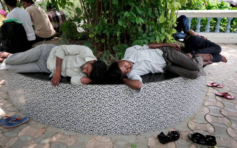Dos viajeros descansan a la sombra de un arbol durante la ola de calor, este martes, en Calcuta, la India. El departamento meteorológico de la India ha activado una alerta para cinco distritos de Calcuta después de que las temperaturas subieran por encima de los 36 grados centígrados. EFE/ Piyal Adhikary