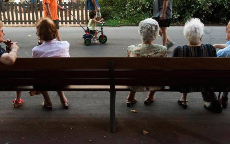 Un grupo de personas mayores, en un banco de una zona verde. / Julio Carbo (Efe)