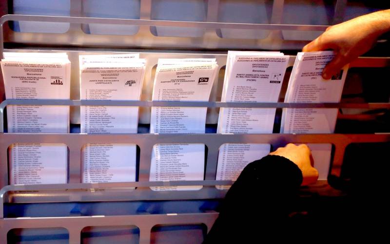 Un operario coloca papeletas electorales en una cabina. EFE/Alberto Estévez
