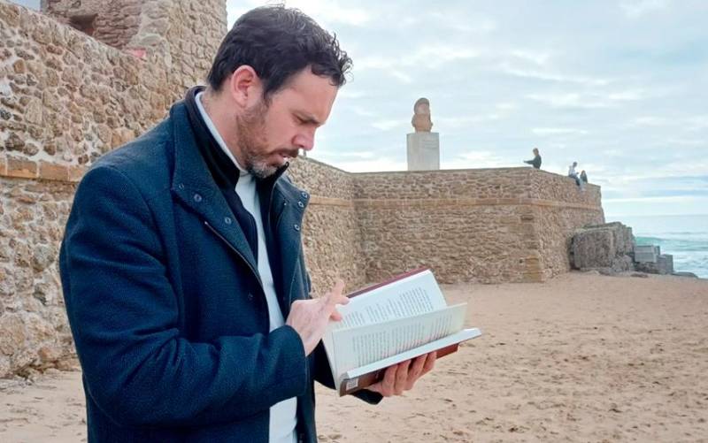 Luis Rossi posa con su novela en la playa de La Caleta en Cádiz junto al busto de Paco Alba.
