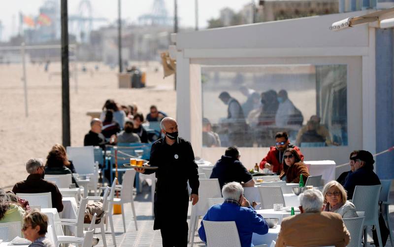 Un camarero atiende las mesas de una terraza en uno de los restaurantes de la playa de la playa de la Malvarrosa de Valencia. EFE/Manuel Bruque