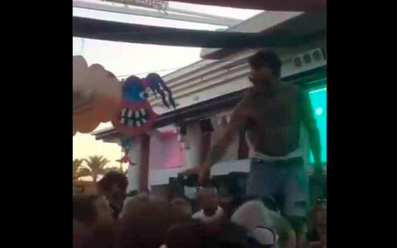 Fragmento del vídeo donde se ve a un DJ dando alcohol de la misma botella a varios asistentes. Previamente, les había escupido.