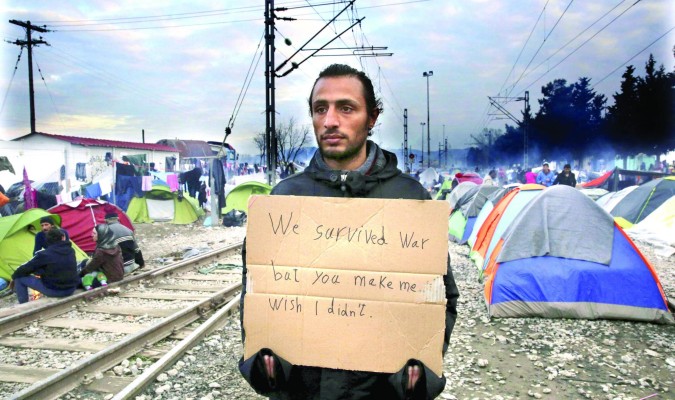 Un refugiado protesta en Idomeni, Su cartel dice: ‘Sobrevivimos a la guerra, pero me hacéis desear que no hubiera sido así’. / Efe