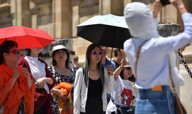 Turistas se protegen del sol con paraguas en Sevilla. / El Correo