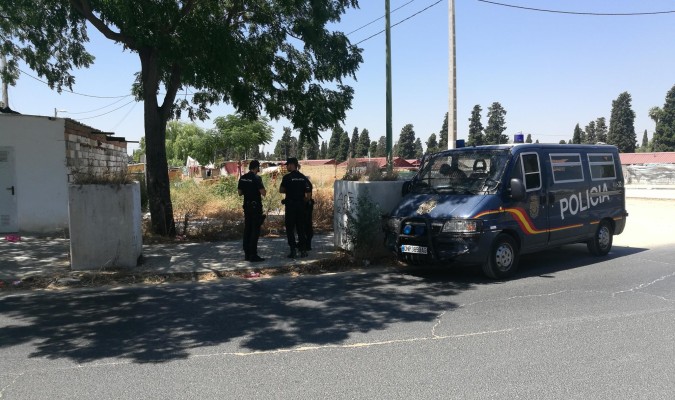 Un furgón de la Policía Nacional y sus agentes vigilan una de las salidas del poblado chabolista del Vacie. / Álvaro García